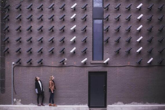 Two people looking at white and black security cameras